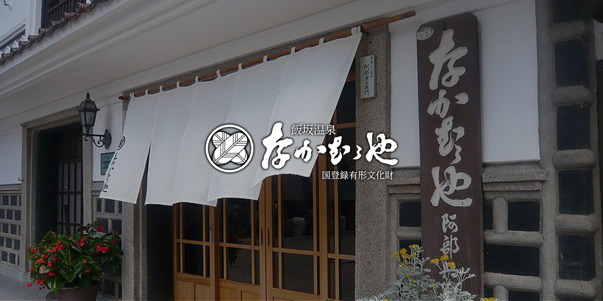 なかむらや旅館 江戸館 — 江戸末期建築の白壁土蔵造り三階建て、家紋「花菱」「丸に違い鷹の羽」の鏝絵が額のように掲げられた正面