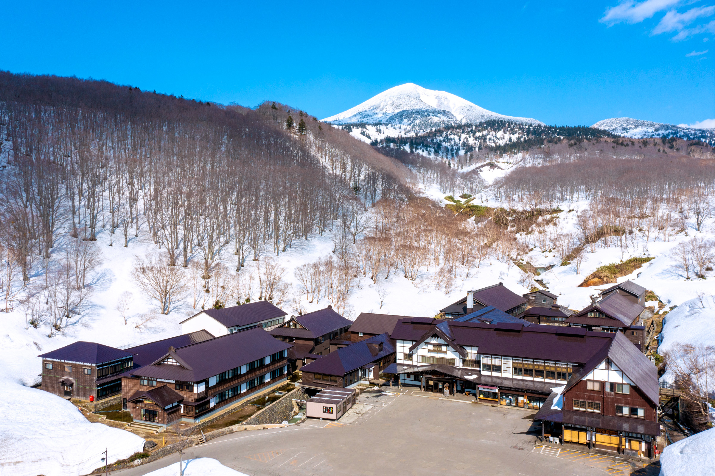 酸ヶ湯温泉旅館 — 青森・八甲田 · 残雪の八甲田大岳を望む木造の本館、1954年に国民保養温泉地第1号指定