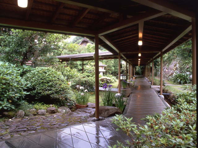 離れ家 石田屋 — 静岡・河津温泉郷 · 庭を貫く飛石と屋根付き回廊が母屋と離れを結ぶ