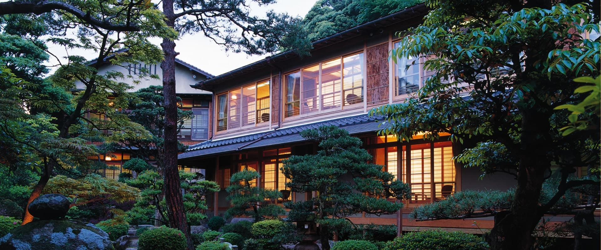 西村屋本館 — 城崎温泉 · 平田雅哉の数寄屋造りと庭園、夕暮れに障子が灯る本館の佇まい