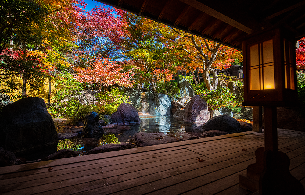 法師温泉 長寿館 — 露天風呂を彩る紅葉と行灯の灯り、みなかみの秋の渓の情景