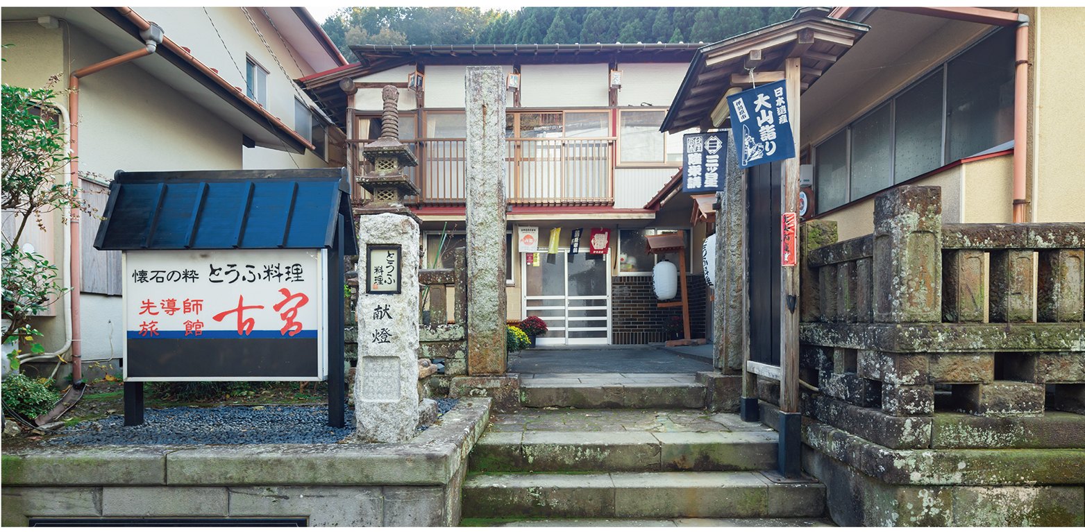 先導師旅館 古宮 — 神奈川県伊勢原市大山 · 参道に面した玄関前に「先導師旅館」の看板と献燈の石柱、右手に講の名を刻む玉垣が並ぶ