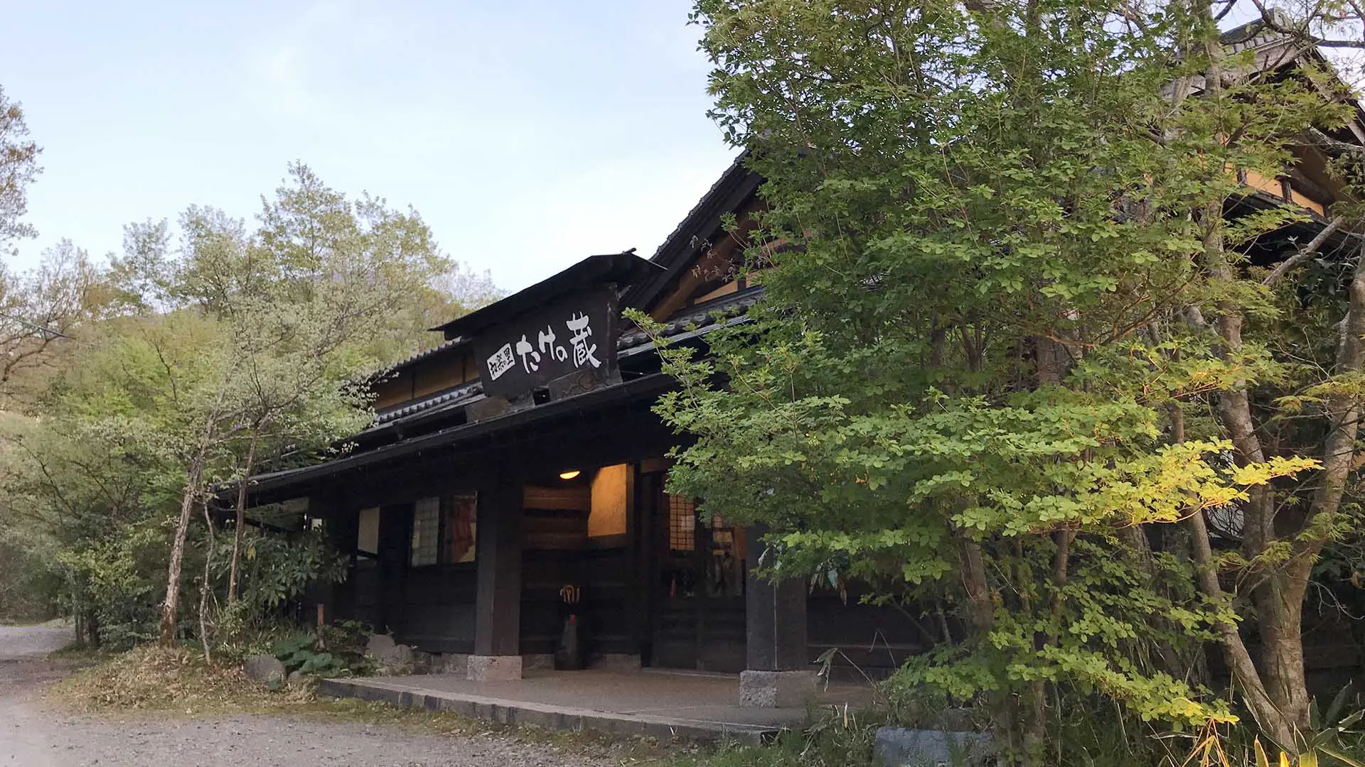 和楽の宿 たけの蔵 — 小国町はげの湯 · 古材を組んだ数寄屋風の棟が木立に囲まれて建つ
