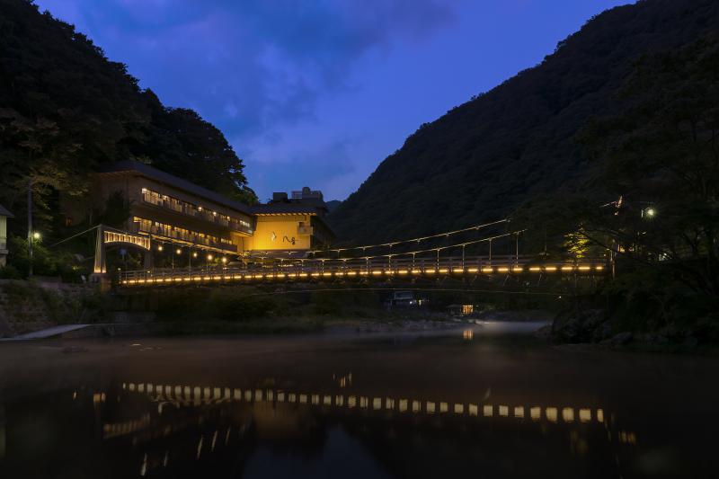 湯原温泉 八景 — 岡山県真庭市湯原温泉 · 旭川の湯かけ橋を望む夕暮れの外観、川面に映る灯り