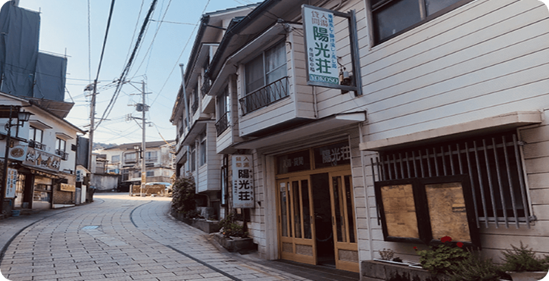 入湯貸間 陽光荘 — 別府・鉄輪いでゆ坂 · 湯けむり漂う路地に建つ木造の貸間湯治宿の外観