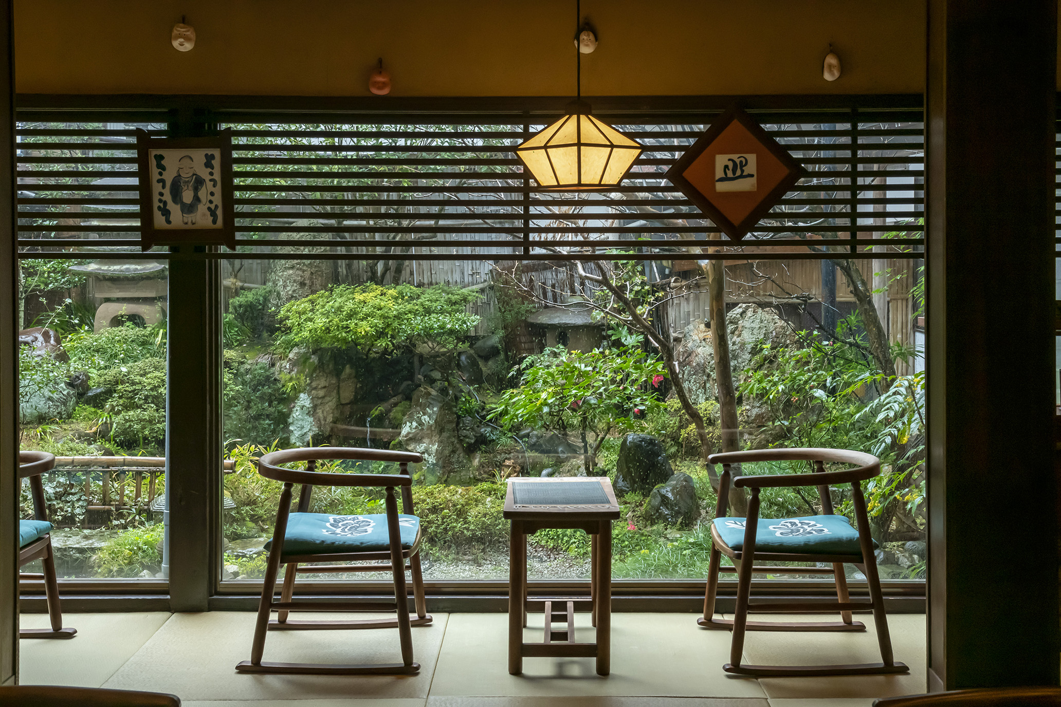 岩井屋 — 中庭を望むティーラウンジ、鳥取民藝の椅子と行灯、簾越しの庭園