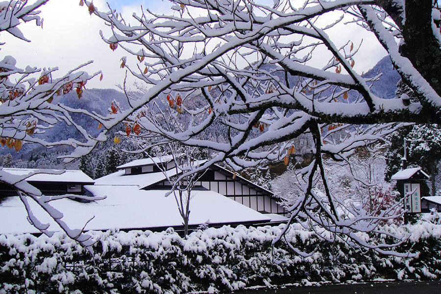 福地温泉 — 岐阜県高山市奥飛騨温泉郷 · 雪に埋もれる山里の切妻屋根と北アルプスの稜線