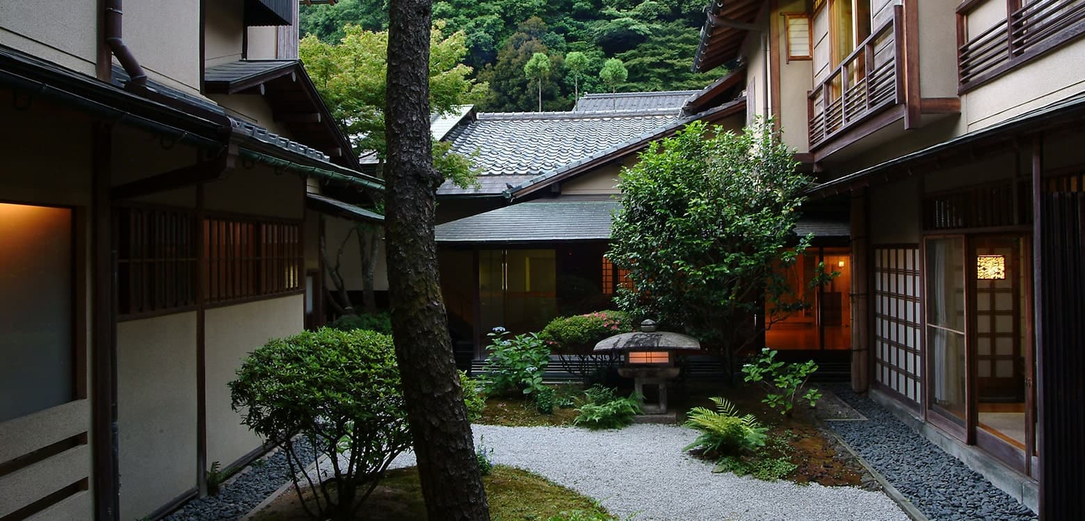 西村屋本館 — 城崎温泉 · 石灯籠と白砂の中庭を囲む木造の客室棟