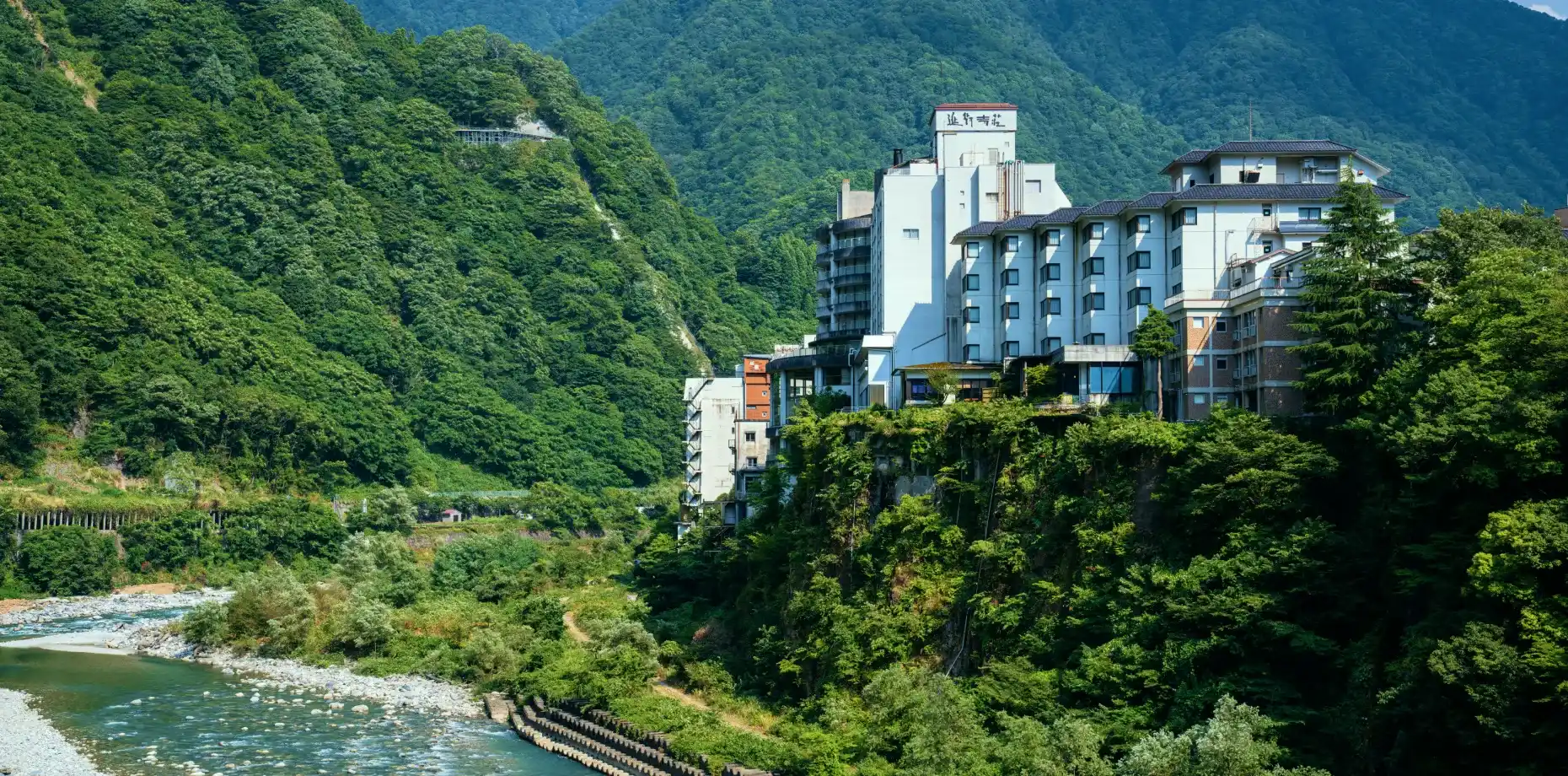 延対寺荘 — 富山県黒部市・宇奈月温泉 · 黒部川本流沿いの崖上に建つ、明治33年創業の宿の外観