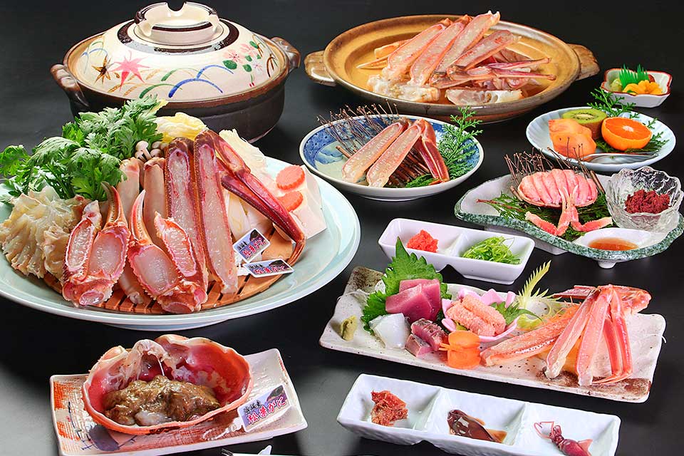 海べのおやど 丸文 — 新温泉町浜坂 · 活松葉蟹のかにすきと蟹刺し、地魚の刺身を並べた冬の会席