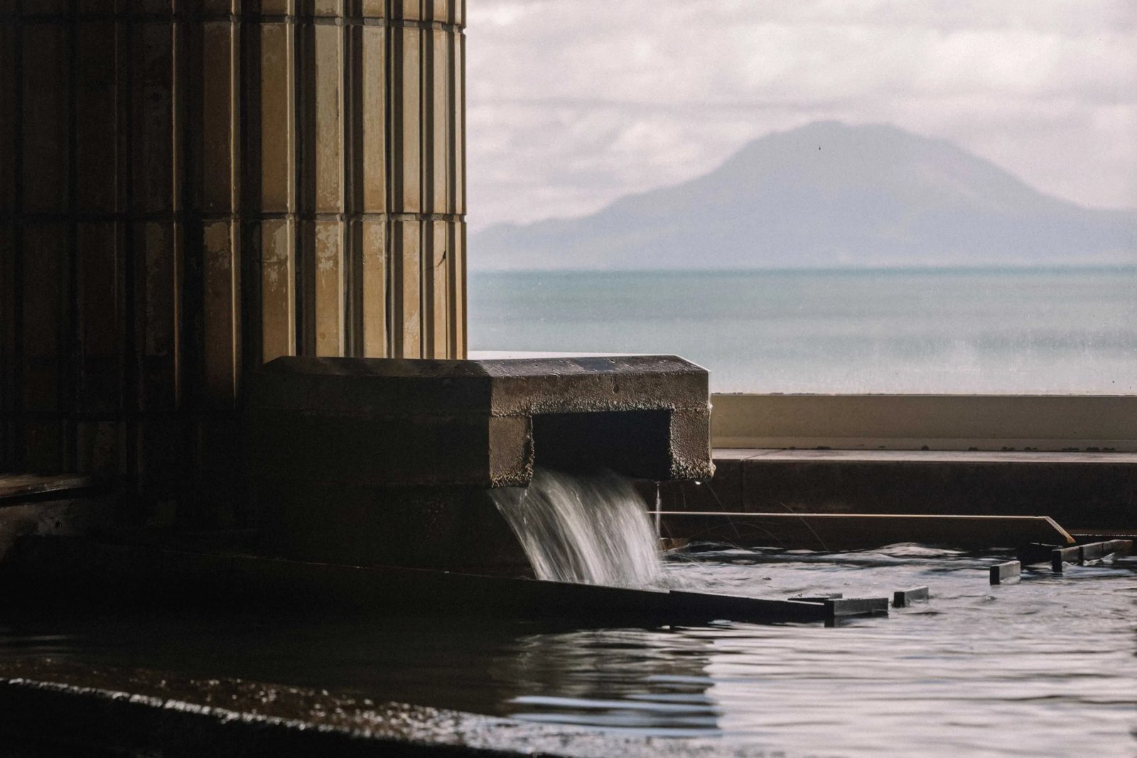 こらんの湯 錦江楼 — 指宿市西方 · 自家源泉が注ぐ湯船の先に錦江湾と対岸の山並み