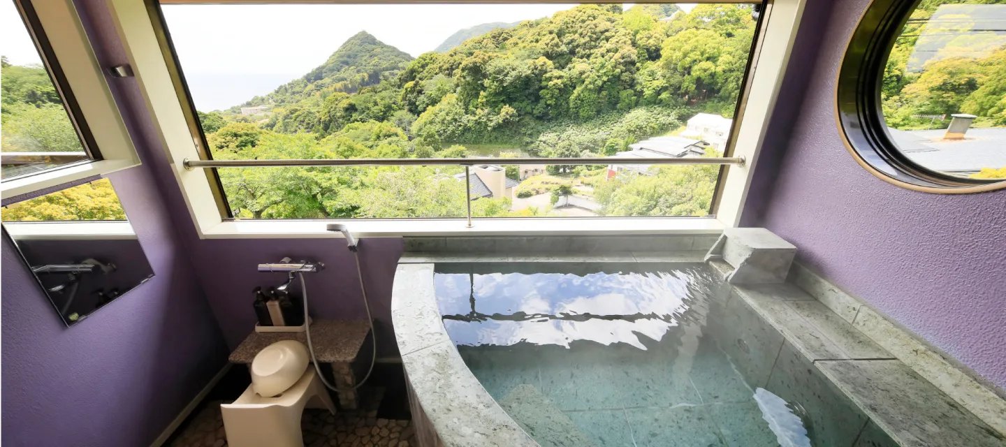 花の風 — 河津町見高・今井浜の高台 · 全4室に備わる全天候型半露天風呂(伊豆石の湯舟と窓越しの山と海)