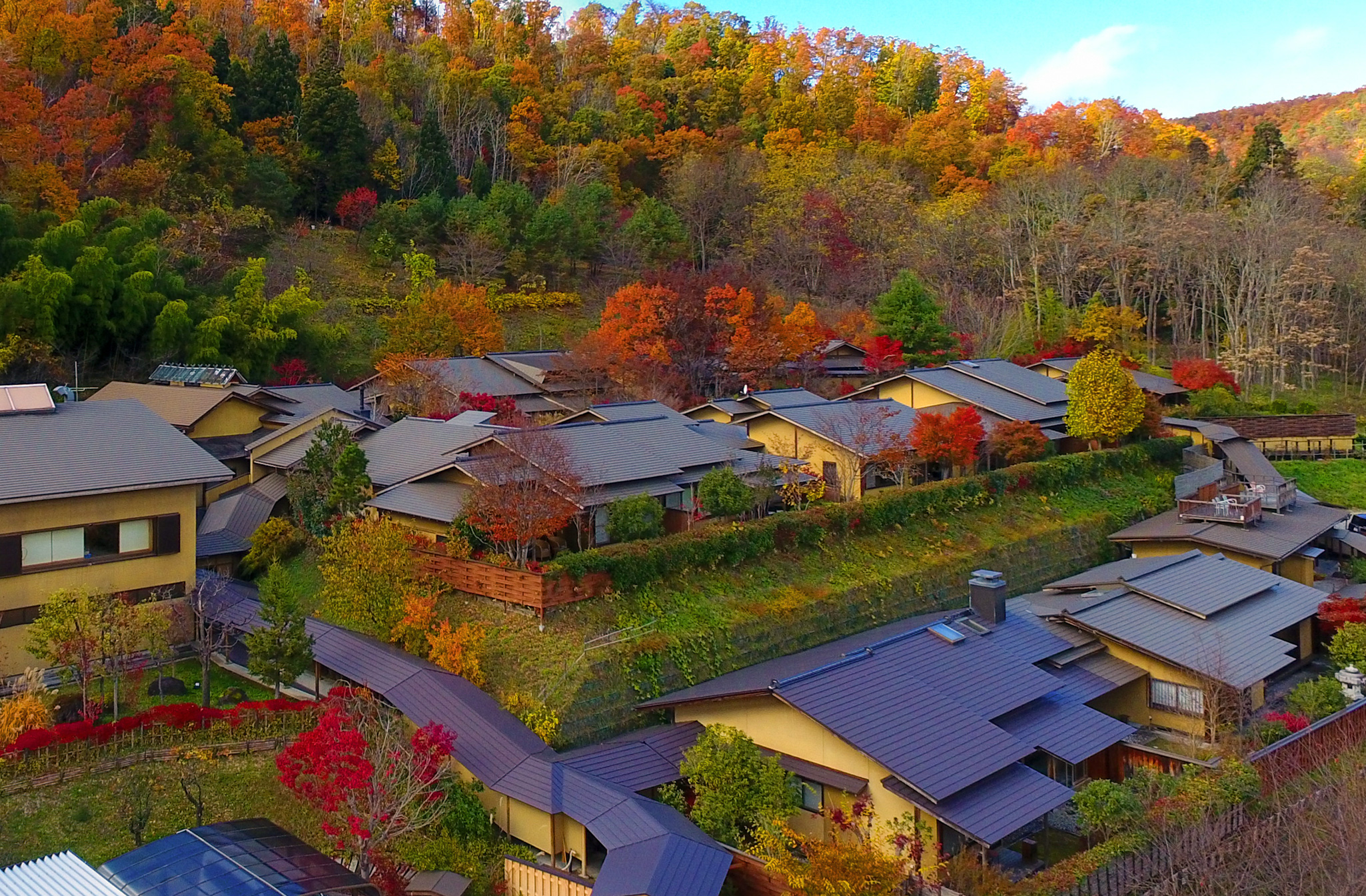 名月荘 — 山形県上山市葉山 · 紅葉の山裾に離れ風の客室棟が点在する宿の全景