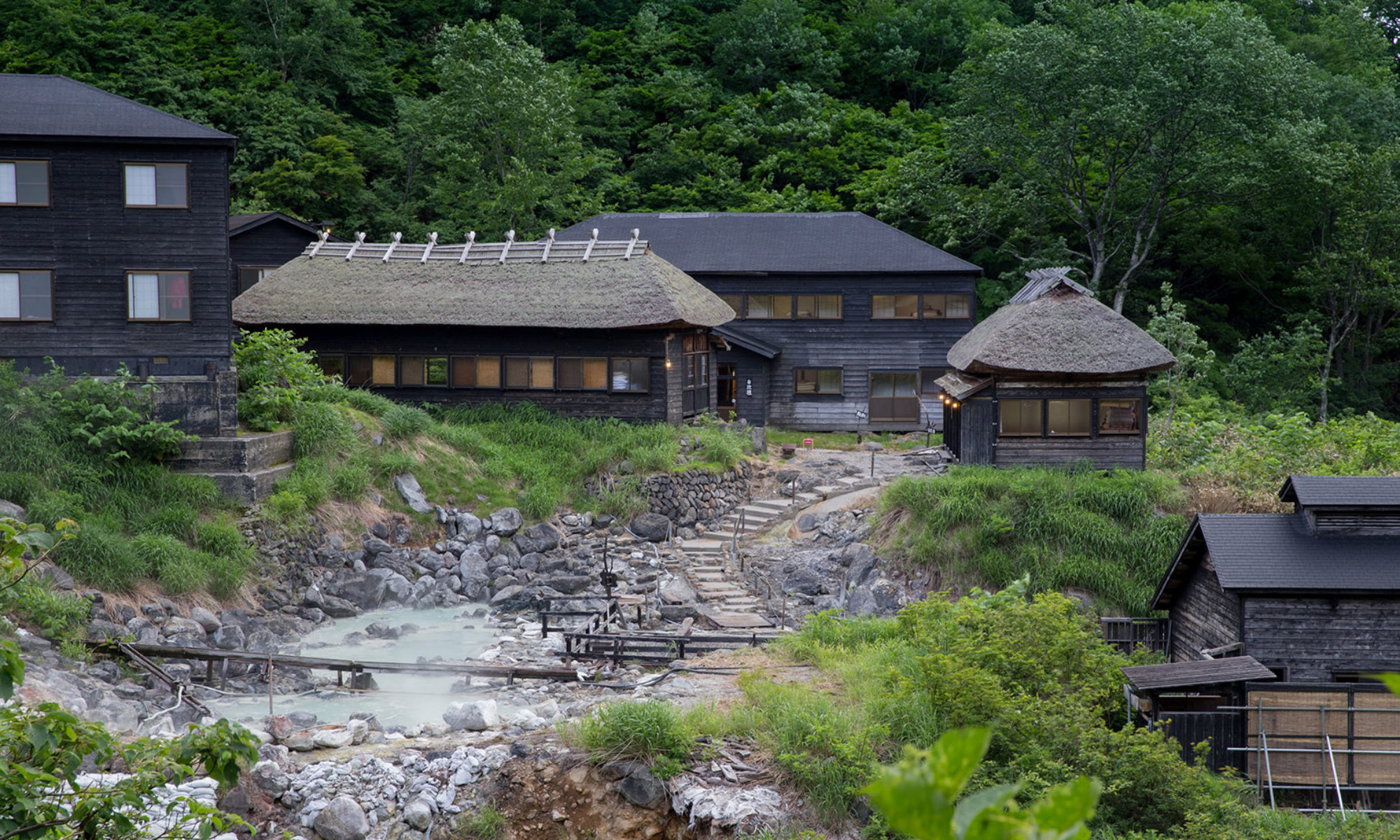 黒湯温泉 — 秋田県仙北市・乳頭温泉郷最奥 · 源泉の湧く河原を囲んで茅葺きと杉皮葺きの黒い宿舎が軒を連ねる湯治場