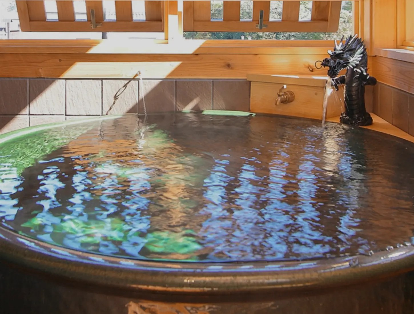 修善寺温泉 五葉館 — 伊豆市修善寺 · 岩組みから湯が流れ落ちる館内の浴室。3つの湯船は貸切で利用できる