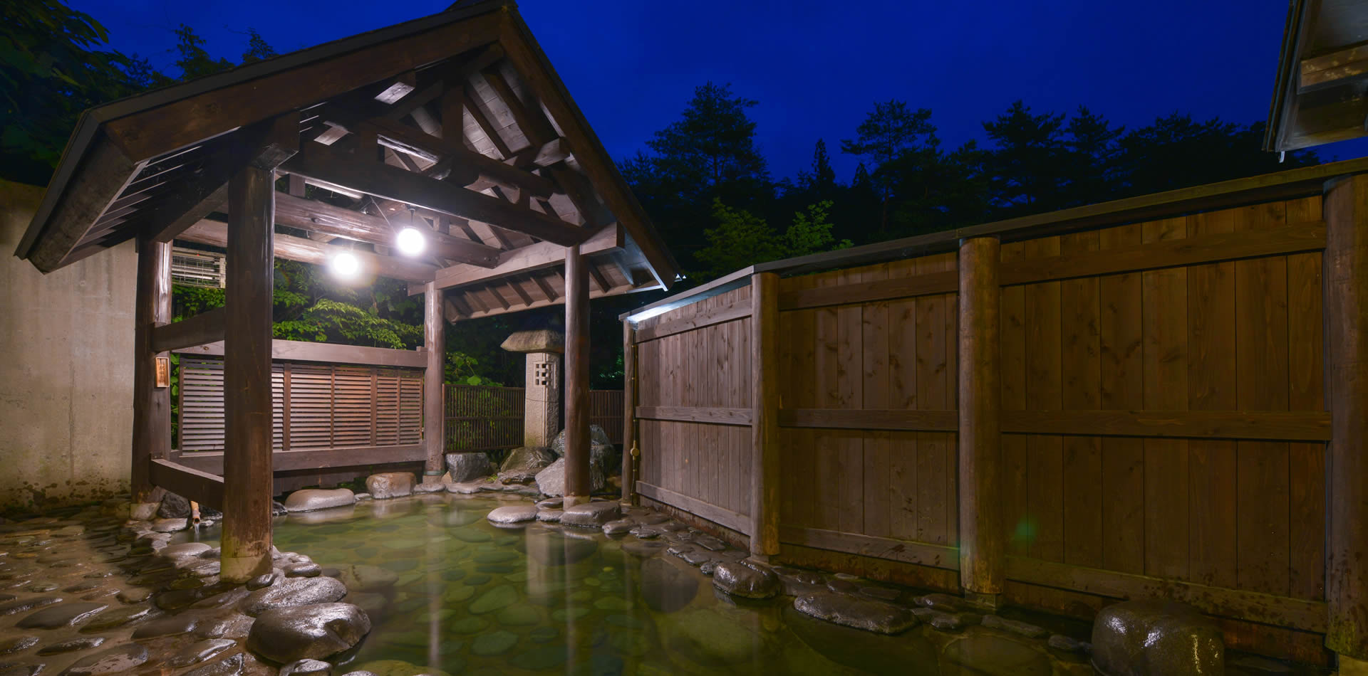 旬樹庵 琢ひで — 大崎市中山平温泉 · 夕暮れに灯がともる屋根付き岩風呂と木塀